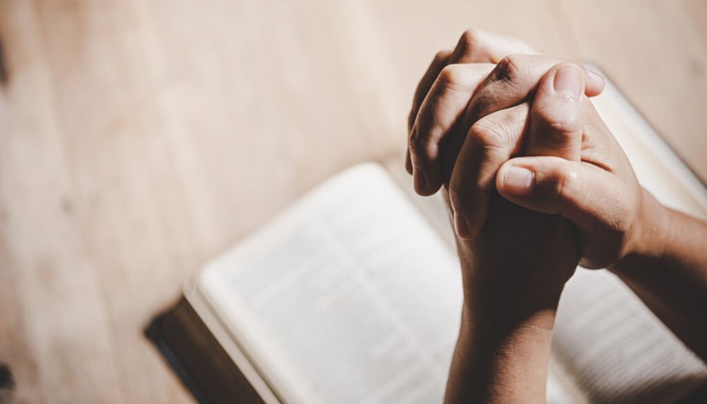 Spirituality and religion, Hands folded in prayer on a Holy Bibl