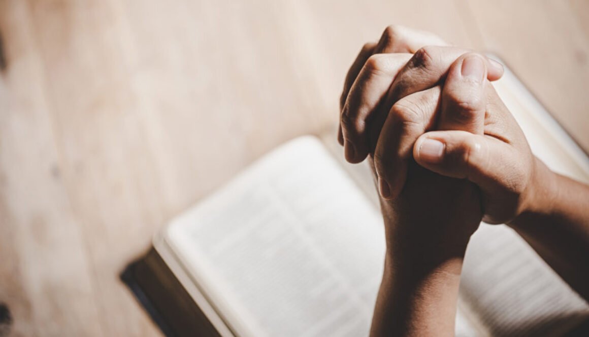 Spirituality and religion, Hands folded in prayer on a Holy Bibl