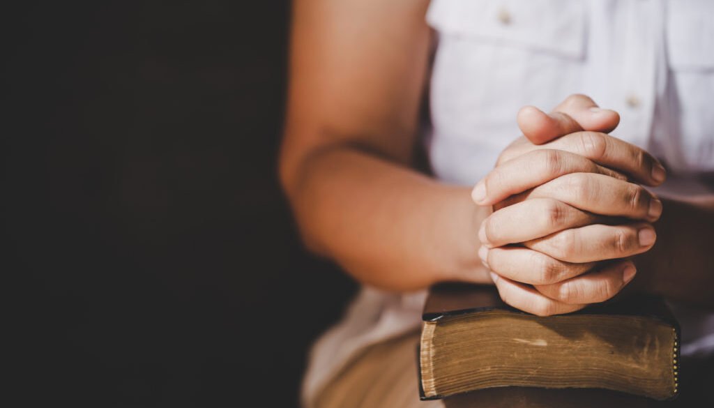 Spirituality and religion, Hands folded in prayer on a Holy Bibl