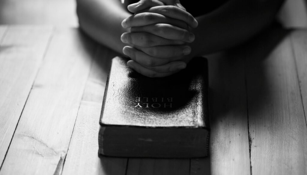 Praying hands of teens on old bible