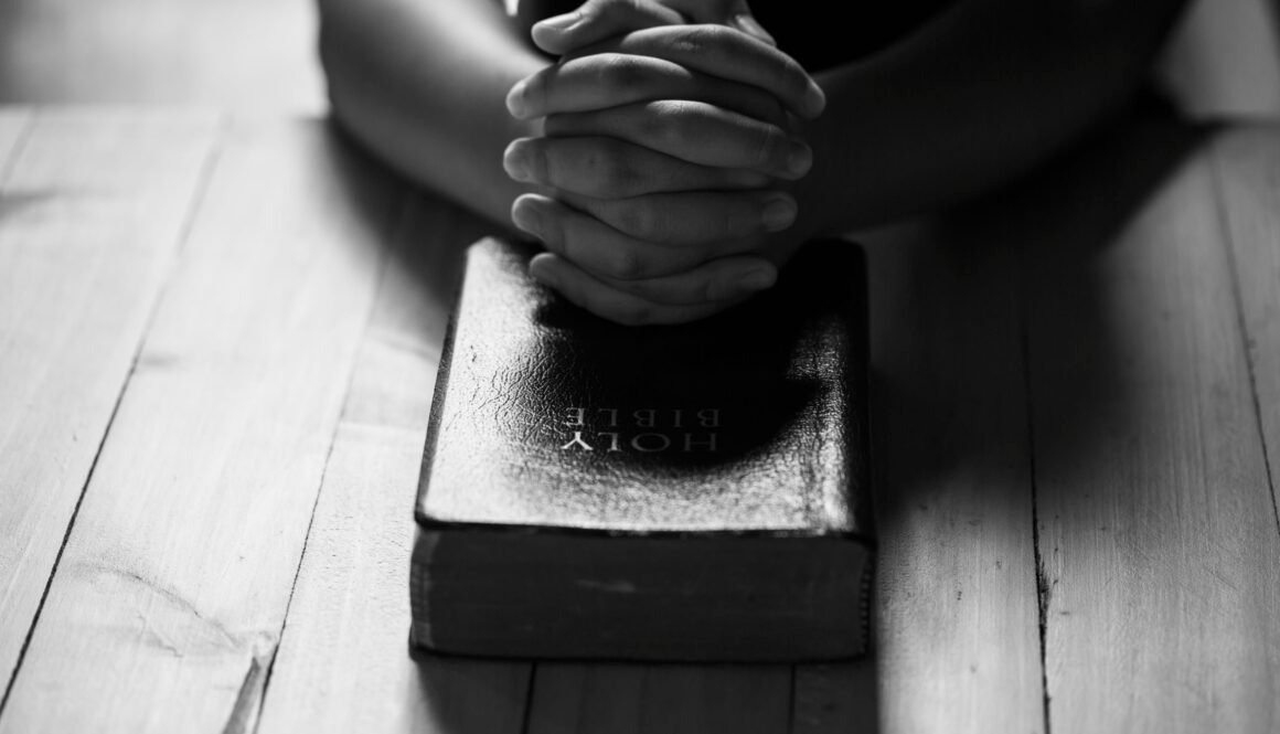 Praying hands of teens on old bible