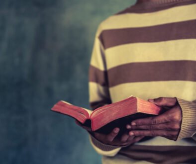 a man standing while reading bible or book over concrete wall wi
