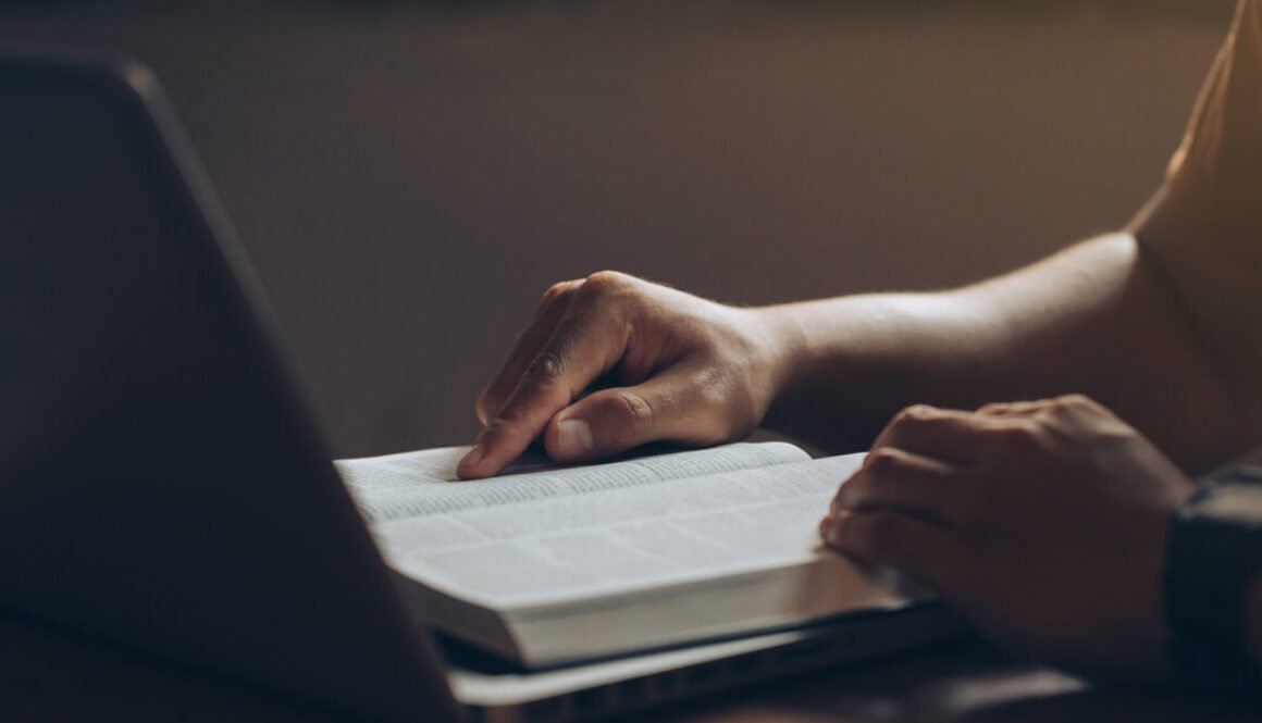 Young men concentrate on reading books with a laptop computer on