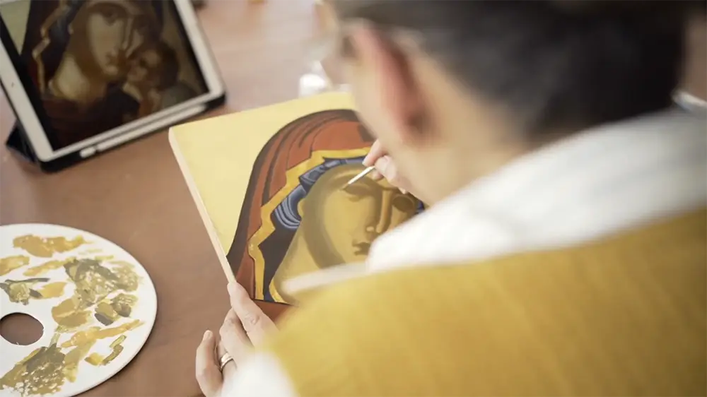 Alumna pintando un icono bizantino de la Virgen María en detalle artístico.